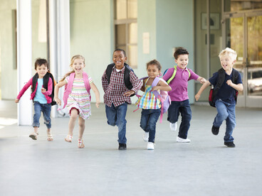 Six écoliers qui courent vers l'école tout sourire